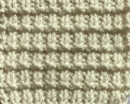 Closeup of the grid knit stitch pattern worked with white pattern