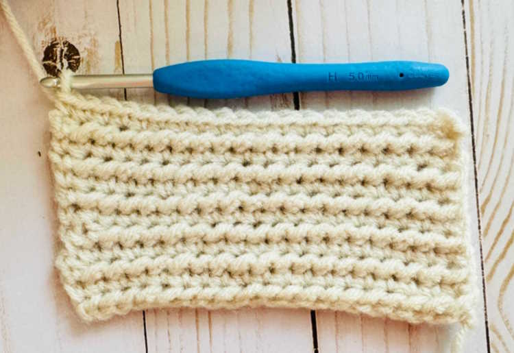 A swatch of the half double crochet knotted stitch worked in white acrylic