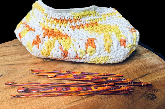 Half double crochet makeup bag with hooks on a black background