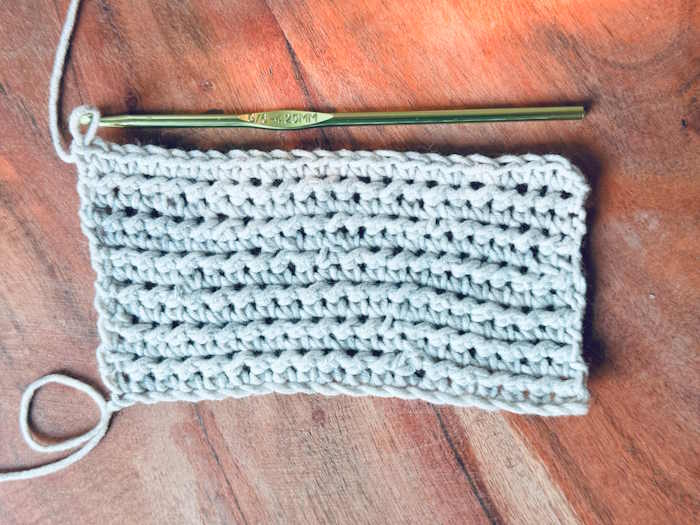 A swatch of the half double crochet knotted stitch worked in grey cotton yarn
