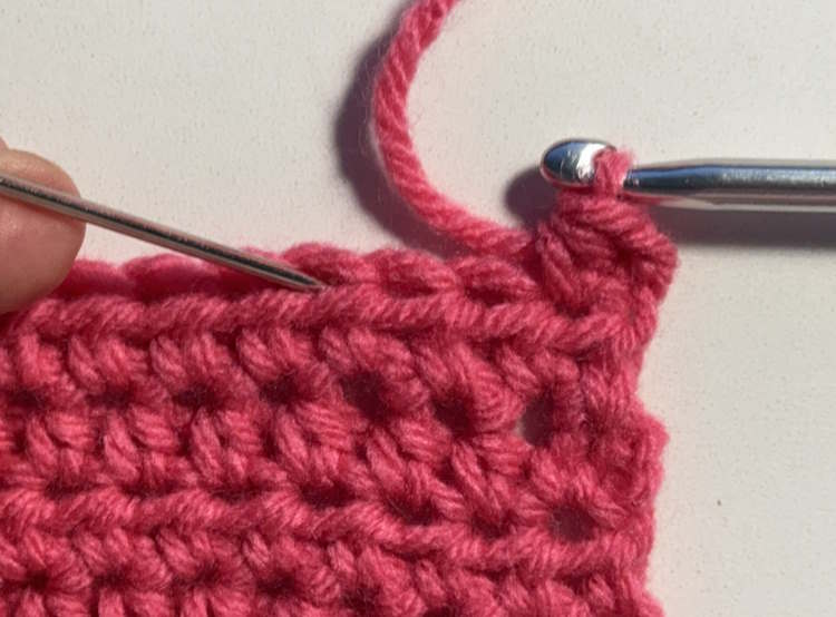Swatch of crochet stitch with a yarn needle showing where to place the hook if working a half double crochet