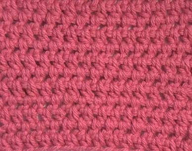 Closeup of a half double crochet offset stitch worked in pink yarn