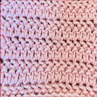 An up close view of the herringbone half double crochet worked in pink yarn