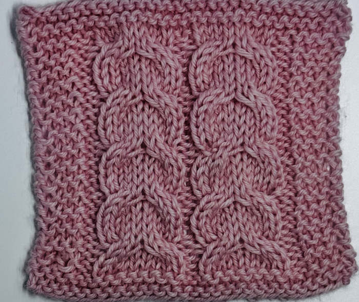 Swatch of the Knitted Horseshoe Cable Stitch Pattern, worked in pink yarn Swatch of the Knitted Horseshoe Cable Stitch Pattern, worked in pink yarn