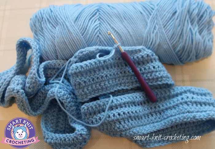 A crochet project is started and still on the hook in blue yarn.