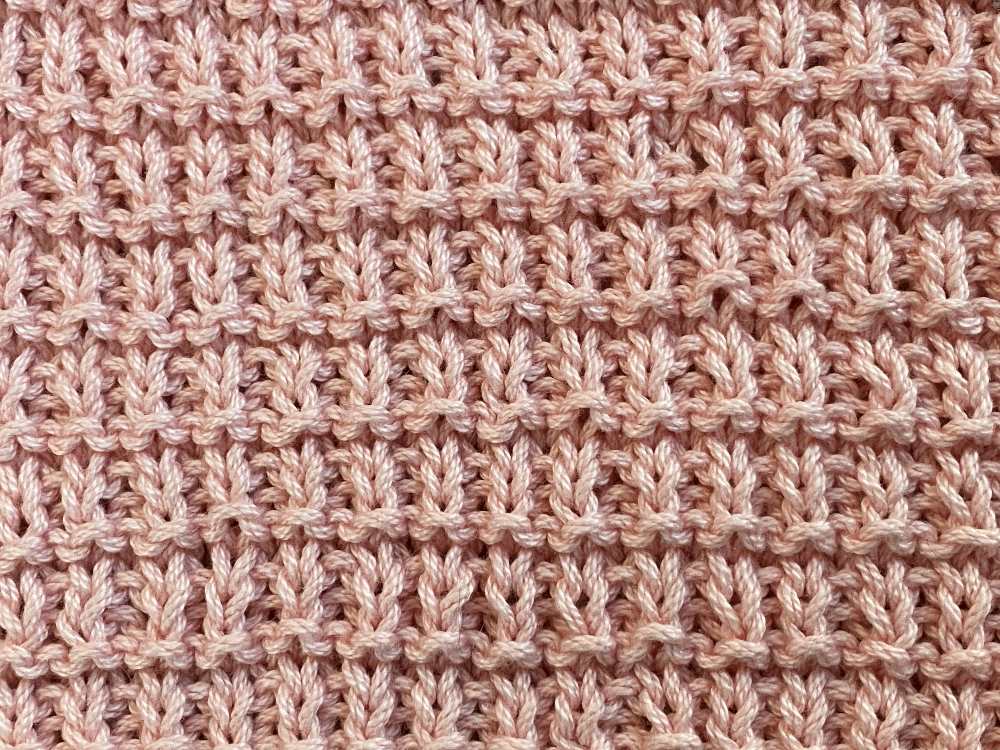 Close up shot of the hurdle knit stitch knitted with pink 100% cotton yarn.