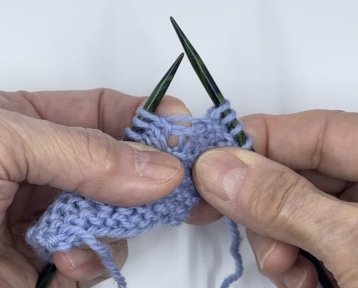 A sample of knitted fabric stretched out to show the bar between stitches where the increases will be made