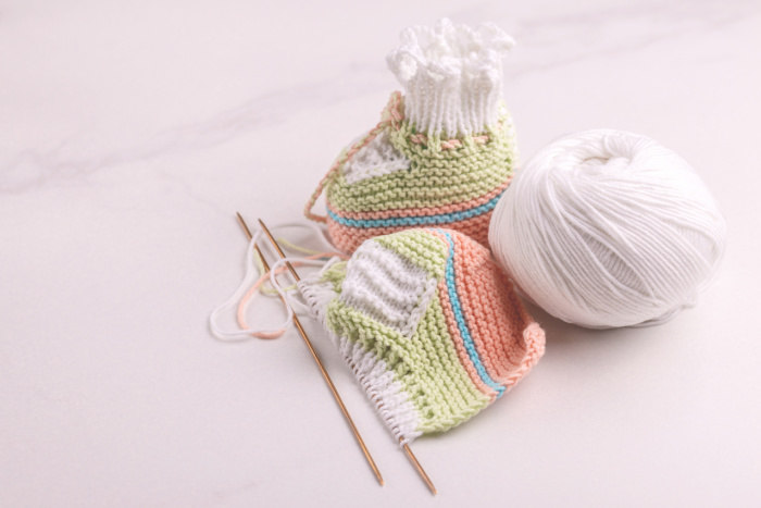 Baby yarn, knitting needles, and booties that are almost finished. Baby yarn, knitting needles, and booties that are almost finished.