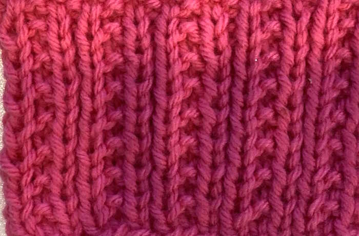 The iron knit stitch pattern worked in red yarn, closeup view