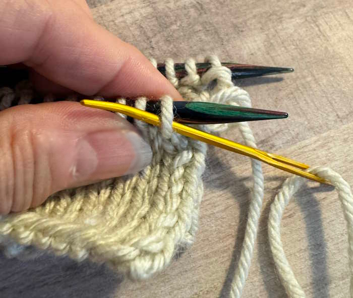 Kitchener stitch showing the tapestry needle being inserted purlwise on the front needle