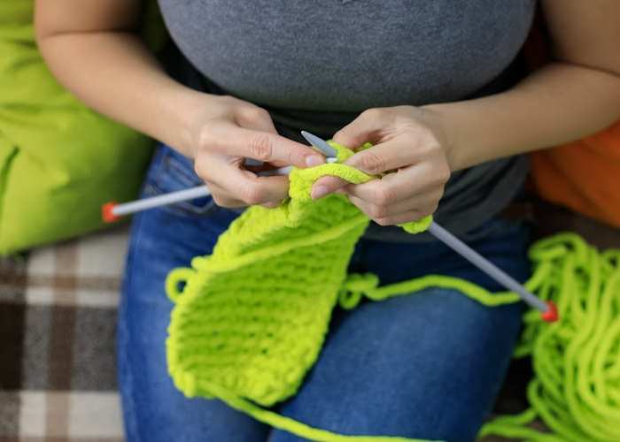 a woman is seated working on a knit scarf a woman is seated working on a knit scarf