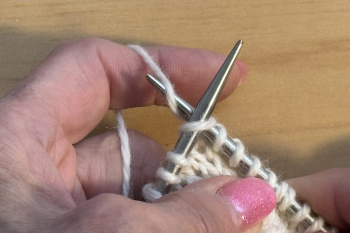 Hands are holding the yarn in the continental style Hands are holding the yarn in the continental style