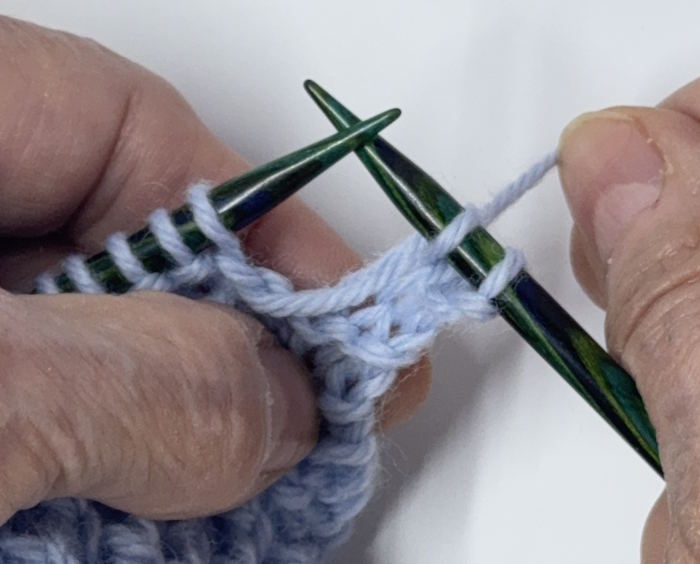 Step four on how to make a knit one below technique
