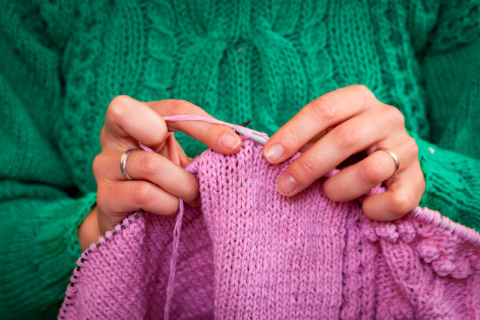 A woman is knitting a seamless sweater on circular needles
