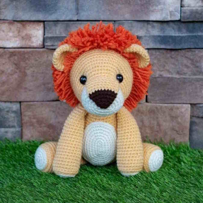 A toy lion crocheted in tan, white and orange yarn