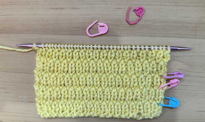 A swatch of the long raindrop knit stitch pattern with stitch markers in place A swatch of the long raindrop knit stitch pattern with stitch markers in place