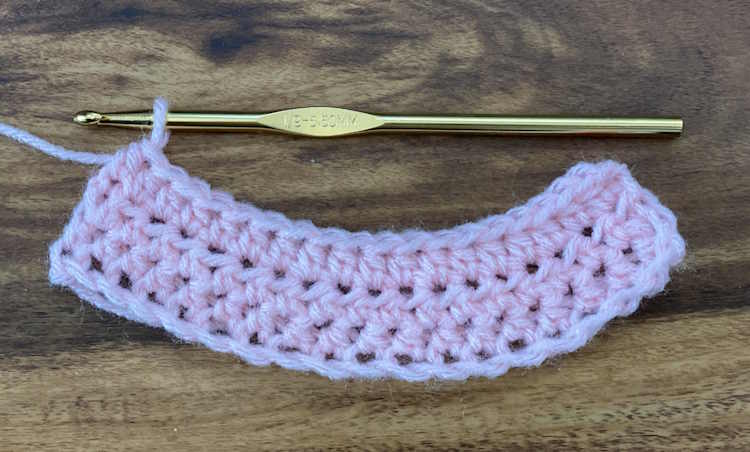 A crochet swatch worked in half double crochet where the beginning chain is too loose.