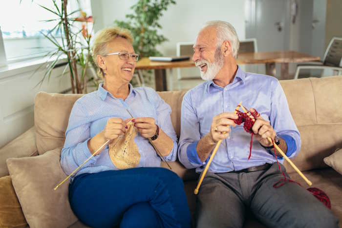 a man and a woman is sitting on a sofa knitting a man and a woman is sitting on a sofa knitting