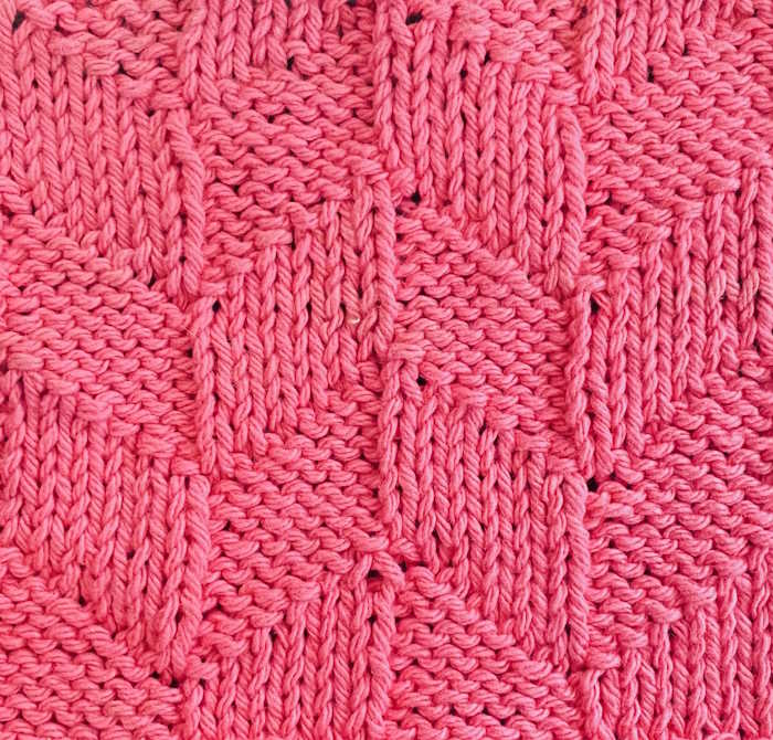 A swatch of the knit parallelogram knit stitch pattern worked in pink showing right side