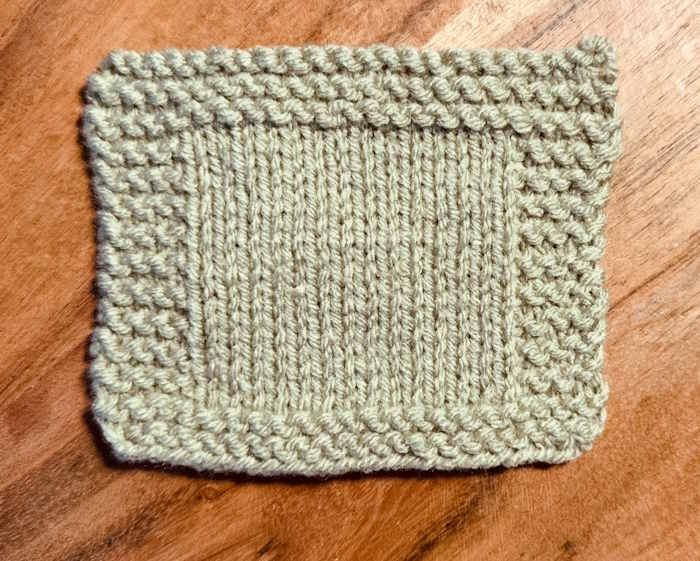 A knitted swatch of Red Heart Supersaver Yarn worked in a green shade A knitted swatch of Red Heart Supersaver Yarn worked in a green shade