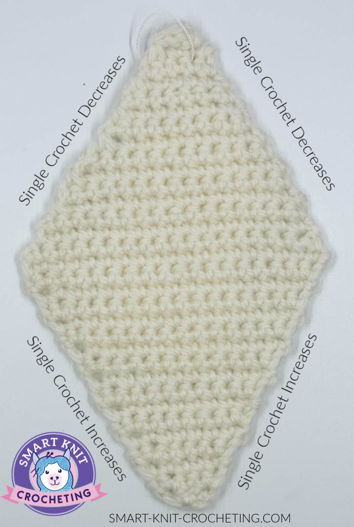 A diamond shape swatch made with single crochet increases and decreases worked in cream colored yarn.