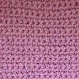 A swatch of single crochet worked in pink acrylic yarn.