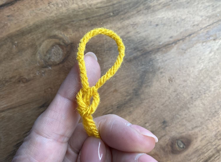 The complete slip knot for knitting held in fingers