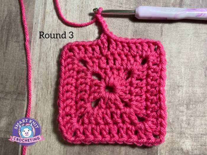 A pink crochet swatch showing 3 rounds completed.