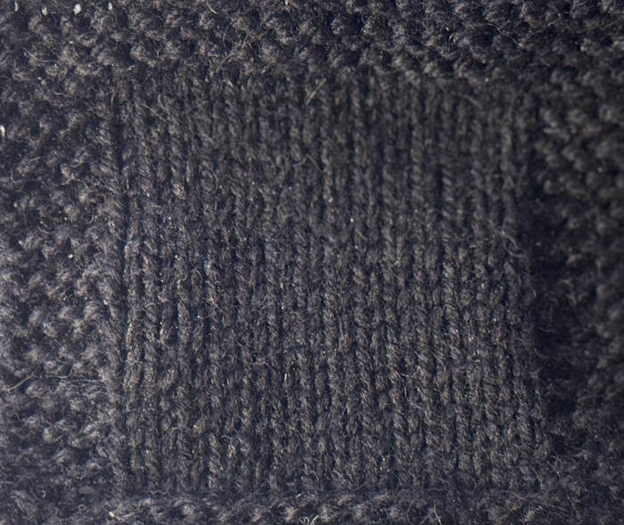 Swatch worked in black yarn making it difficult to see stitch definition
