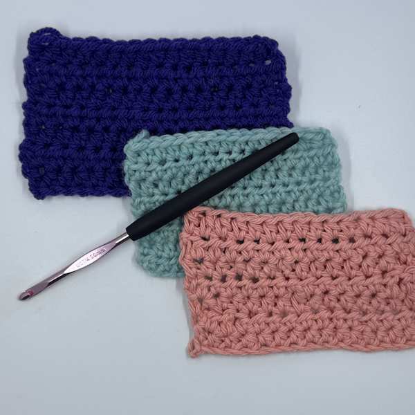 A Susan Bates ergonomic crochet hook with three swatches