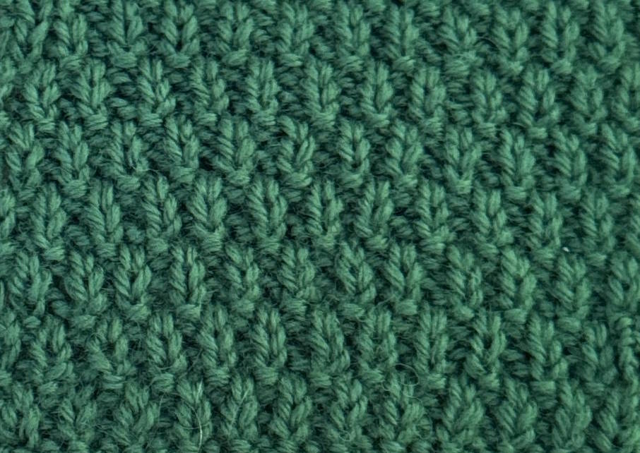 Wrong side of a green wool Swift Stitch knitting swatch, showing its knit-and-purl texture.