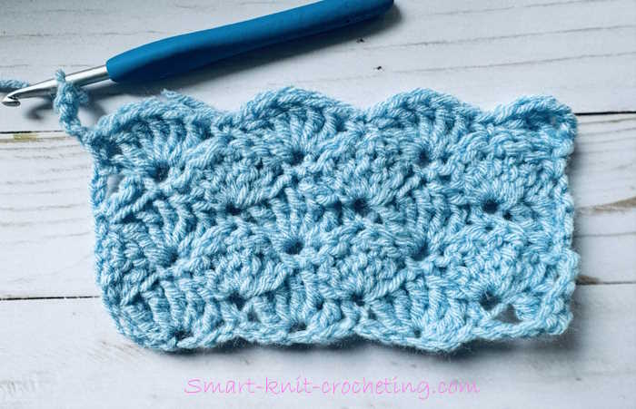 A swatch of treble crochet shell stitch worked in blue acrylic yarn A swatch of treble crochet shell stitch worked in blue acrylic yarn