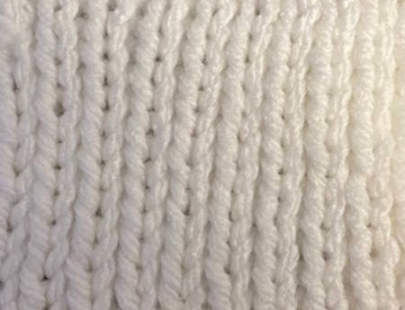 Twisted rib stitch pattern worked in white acrylic yarn, wrong side Twisted rib stitch pattern worked in white acrylic yarn, wrong side