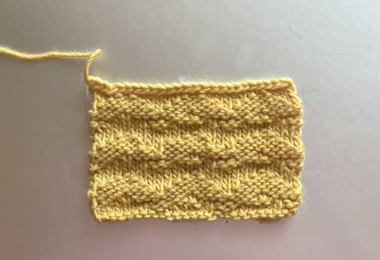 Waved welt knit stitch swatch worked in gold color yarn, showing right side Waved welt knit stitch swatch worked in gold color yarn, showing right side