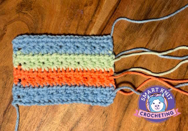 A crochet swatch worked in several different colors showing the ends that need to be woven in.