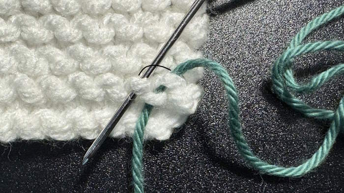 Step two is of weaving in ends in the garter stitch pattern where the needle is placed under the next frown to the left