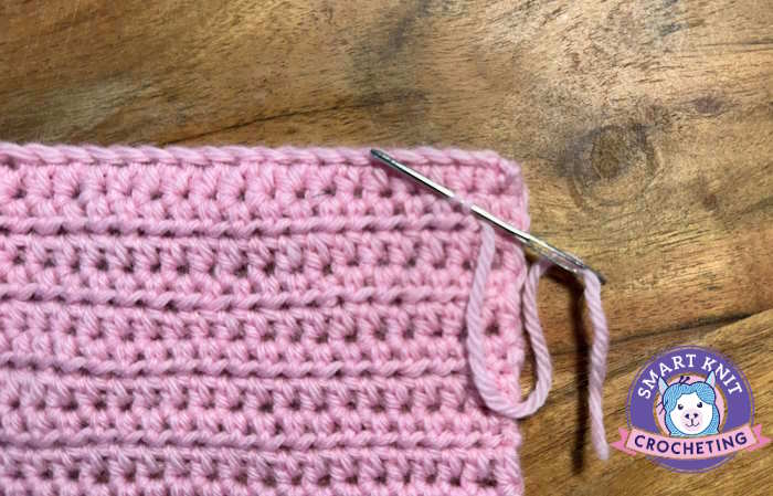 A swatch of half double crochet showing a tapestry needle weaving in ends