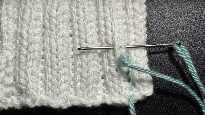 This demonstrates the second step for weaving in ends in knit ribbing stitches