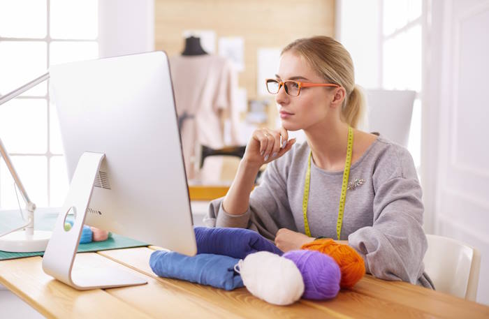 A young woman is studing something on her computer as she begins to create a design. A young woman is studing something on her computer as she begins to create a design.