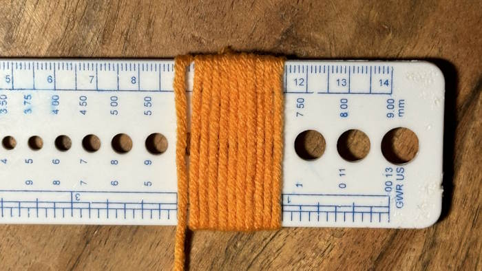 A ruler wrapped in yarn showing how to calculate the wpi