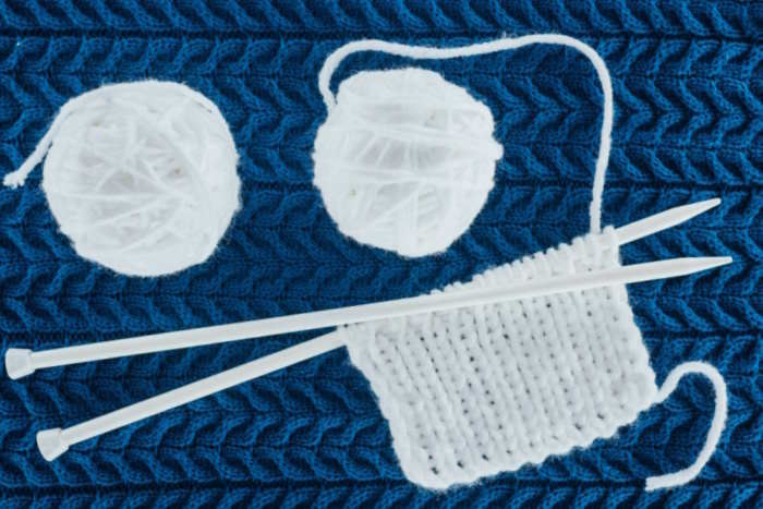 Beginner knitting: hands holding needles working the knit stitch